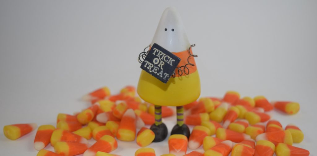 Candy corn figurine with sign saying trick or treat